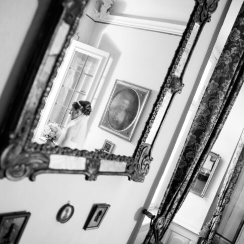 Herrschaftlicher Raum, in dem ein Spiegel hängt, in dem sich die Braut spiegelt, wie sie aus einer Tür tritt