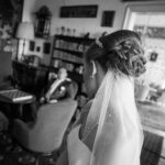 Herrschaftlicher Wohnraum, in dem der Bräutigam im Hintergrund auf einem Sessel sitzt und die Braut im Vordergrund zu ihm blickt