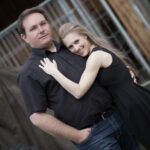 Paar steht Arm in Arm und schaut in die Kamera