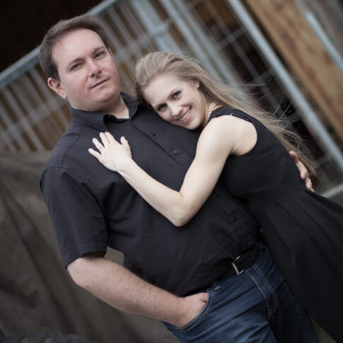 Paar steht Arm in Arm und schaut in die Kamera