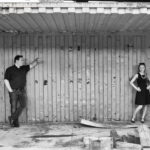 Paar steht in Flirthaltung in einem Container