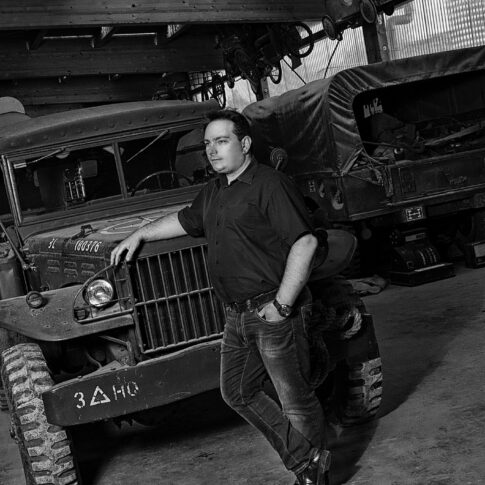 In einer Garagenhalle lehnt der Mann nachdenklich an der Motohaube eines Geländewagens